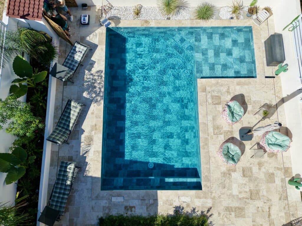 Piscine de Luxe avec Terrasse en Pierre et Transats Vue aérienne d'une piscine rectangulaire turquoise avec terrasse en pierre, transats et mobilier de jardin moderne.