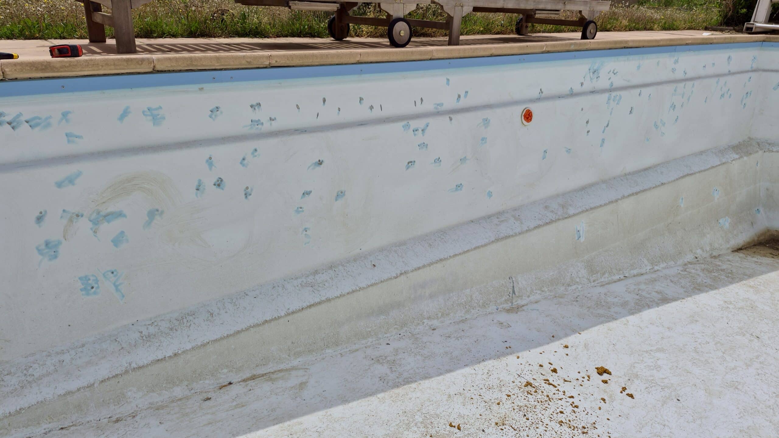 Parois d'une piscine vide avec marquages bleus pour travaux de rénovation et entretien du revêtement.
