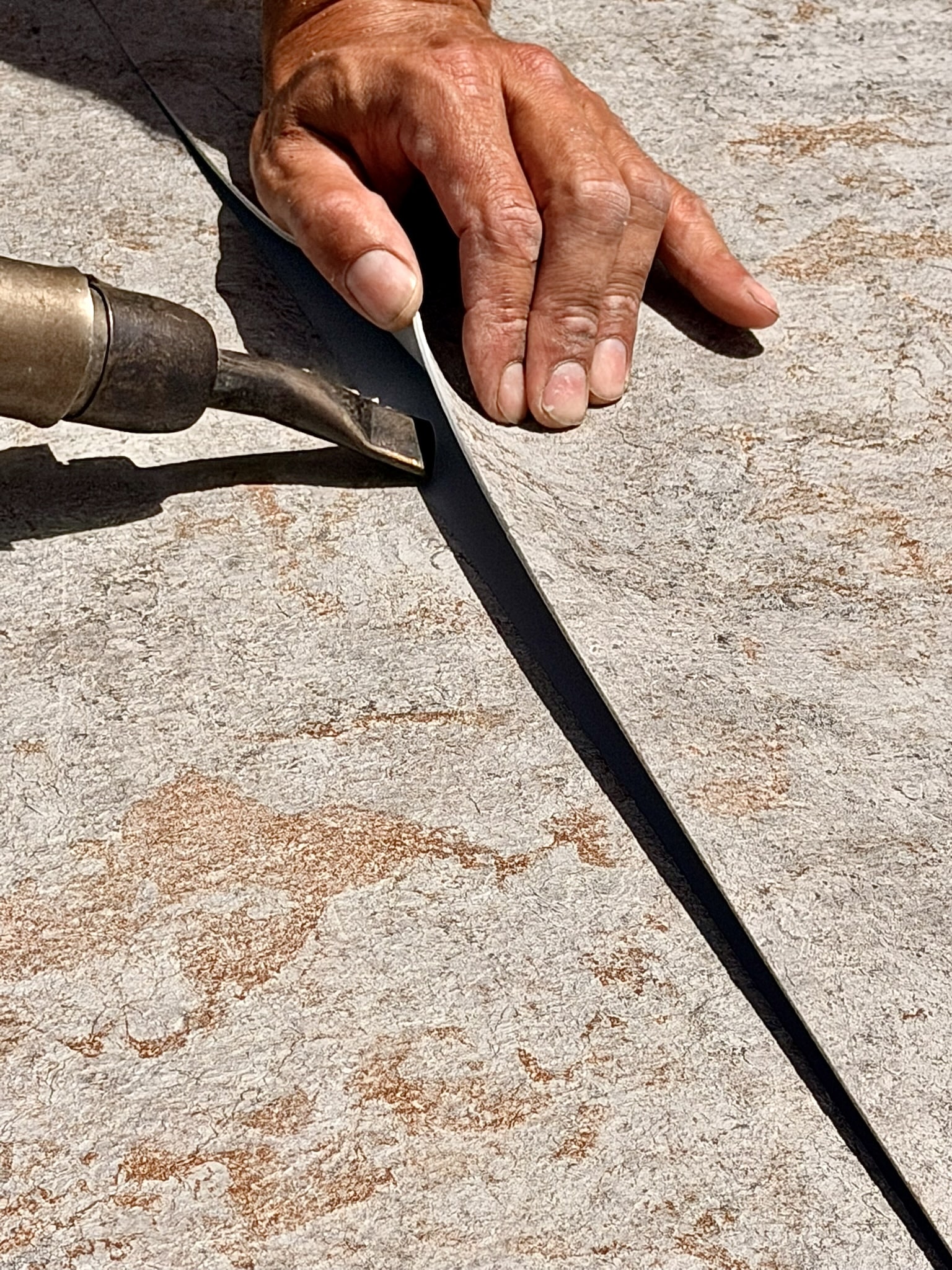 Soudure à chaud d'un joint de sol PVC par un artisan avec un outil de précision.